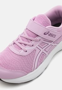 Chaussure de sport violette avec tige en maille, lacets élastiques et bande Velcro. Caractéristiques d'accents blancs et d'une semelle rembourrée. Logo de la marque affiché.