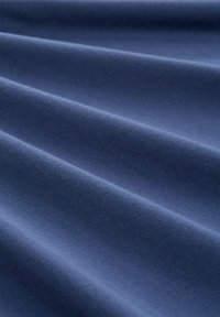 Granatowa tkanina o gładkiej fakturze, z delikatnymi fałdami i jednolitym, miękkim wyglądem. Brak widocznych wzorów lub elementów metalowych.