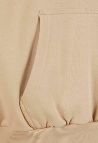 Felpa beige con tasca a canguro, orlo a coste e tessuto testurizzato. Materiale morbido con leggero elasticità per il massimo comfort.