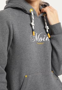 Grå huvtröja med snoddar som har gula och svarta accenter. Framlomma med ficka och "Moin"-text i vitt tryckt. Mjuk, texturerad tyg.