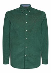 Camisa de pana verde con mangas largas, cuello abotonado y botones delanteros. Presenta un patrón texturizado sutil y un pequeño logo en el pecho.