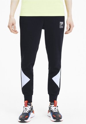 Czarne spodnie dresowe z białymi ukośnymi panelami, elastyczną talią i prążkowanymi ściągaczami. W połączeniu z wielokolorowymi butami sportowymi.
