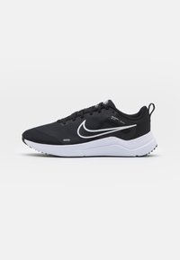 Scarpe sportive nere con tomaia in mesh testurizzata, logo swoosh bianco e suola bianca. Presentano un design con lacci e una linguetta sul tallone per una facile calzata.