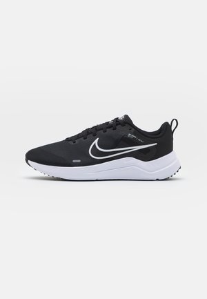 Czarne buty sportowe z teksturowaną siateczką u góry, białym logo Swoosh i białą podeszwą. Charakteryzują się sznurowanym zapięciem oraz pętelką z tyłu dla łatwego zakładania.