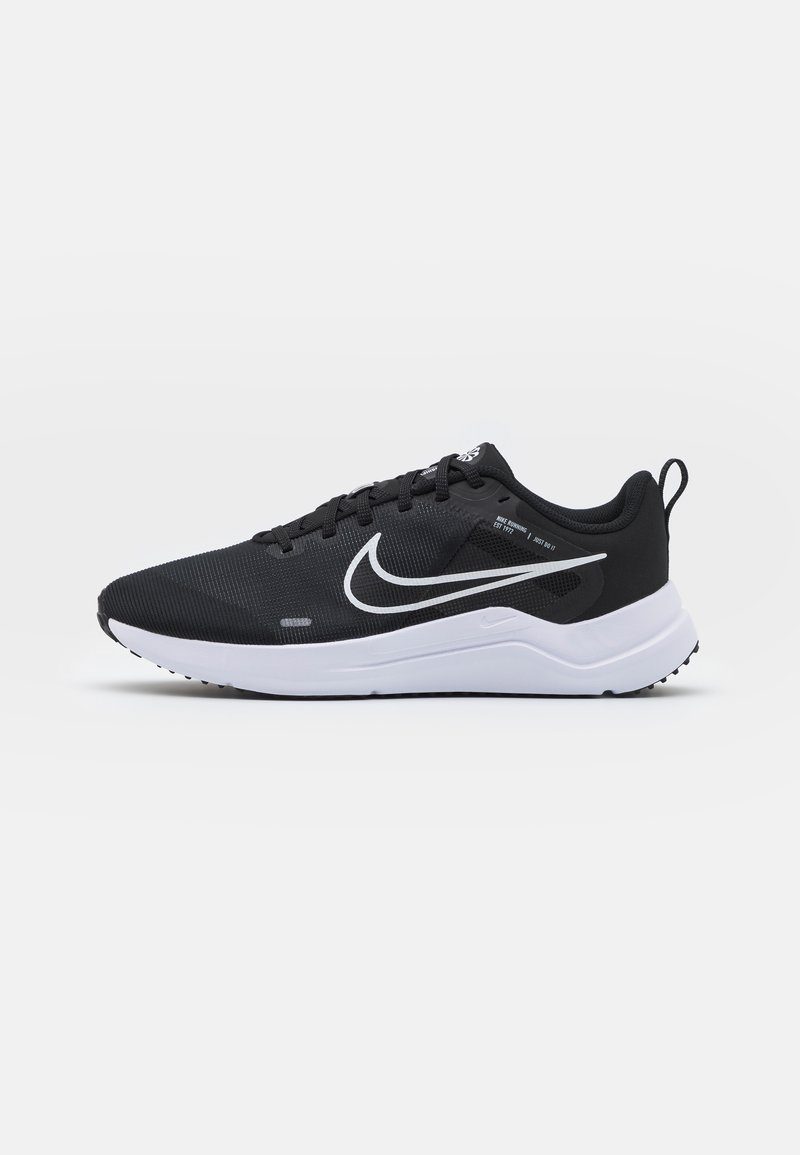 Scarpe sportive nere con tomaia in mesh testurizzata, logo swoosh bianco e suola bianca. Presentano un design con lacci e una linguetta sul tallone per una facile calzata.
