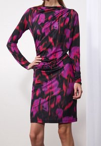 Abito a maniche lunghe in tessuto nero con un vivace motivo astratto rosa e rosso. Forma aderente con dettagli arricciati in vita.