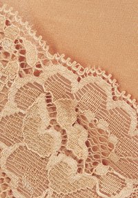 Spitzenbesatz mit filigranem Blumenmuster in hellbeige, übereinander gelegt auf glattem Pfirsichstoff, der detaillierte Nähte und Textur zeigt.