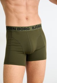 Zelené pánske boxerky olivovej farby s čiernym pásom, na ktorom sa nachádza logo "BJÖRN BORG". Mäkko, elastické tkaniny a priliehajúci strih.