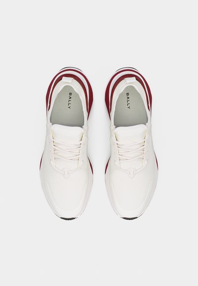 Paire de baskets blanches Bally avec des accents rouges et des lacets, vue de dessus sur un fond uni.