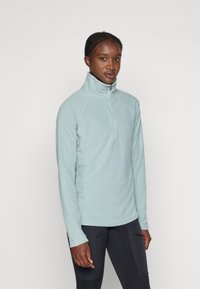 Pullover in pile azzurro chiaro con colletto alto e chiusura a metà zip. Presenta maniche lunghe e una superficie morbida e testurizzata.