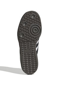 Svart gummisneakersula med ett texturerat geometriskt mönster, med cirkulära grepp och en präglande "adidas"-logotyp.