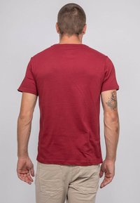 T-shirt court à manches courtes de couleur bordeaux, fabriqué en tissu doux, avec un col rond et un dos épuré sans graphismes ni embellissements.