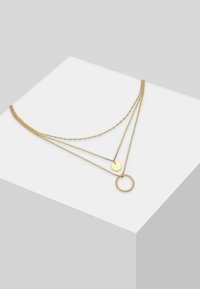 Collier multi-couches en or comportant des chaînes fines et torsadées, avec un pendentif circulaire lisse et un accent en forme de bague texturée.
