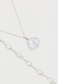 Collier en argent avec un grand pendentif clair en forme de cœur facetté et un bracelet assorti avec des pierres claires en forme de marquise.