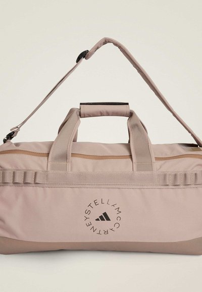 Ροζ ανοιχτό σακ βουαγιάζ από ανθεκτικό ύφασμα, με δύο ανθεκτικές λαβές, αποσπώμενο λουράκι, εκτύπωση λογότυπου και οριζόντια τσέπη με φερμουάρ.