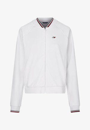 Chaqueta blanca con cremallera completa, cuello y puños acanalados con rayas rojas, negras y blancas, y un pequeño logo en rojo, negro y blanco en el pecho.