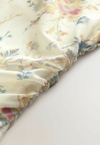Blumenerstoff mit einem hellen cremfarbenen Hintergrund und pastellfarbenen Blüten. Das Material ist weich mit gerafften Kanten und zeigt komplizierte Muster.