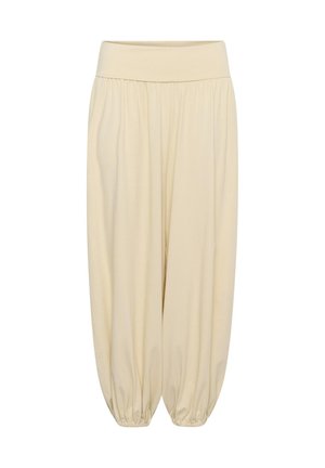 Luźne beżowe spodnie z szerokim elastycznym pasem i marszczonymi elastycznymi mankietami przy kostkach, tworzące sylwetkę balonową.