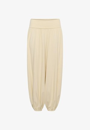 Pantalones sueltos beige con cintura ancha elástica y puños elásticos fruncidos en los tobillos, creando una silueta de globo.