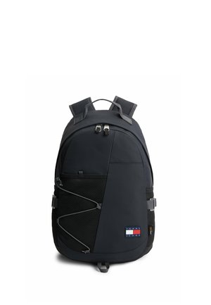 Zaino nero Tommy Jeans con spallacci imbottiti, tasca anteriore in rete con cordino elastico e scomparto principale con zip su sfondo bianco.