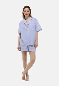 Ensemble de pyjama à rayures bleues et blanches avec un haut à boutons et un short, présentant une poche poitrine et une texture de tissu douce.