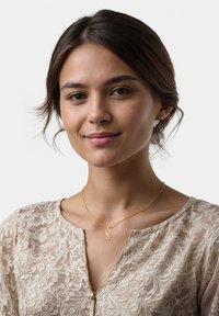 Guldhalsband med cirkulär berlock, bärs av en modell. Modellen har på sig en ljusfärgad topp med blommönster och V-ringning.