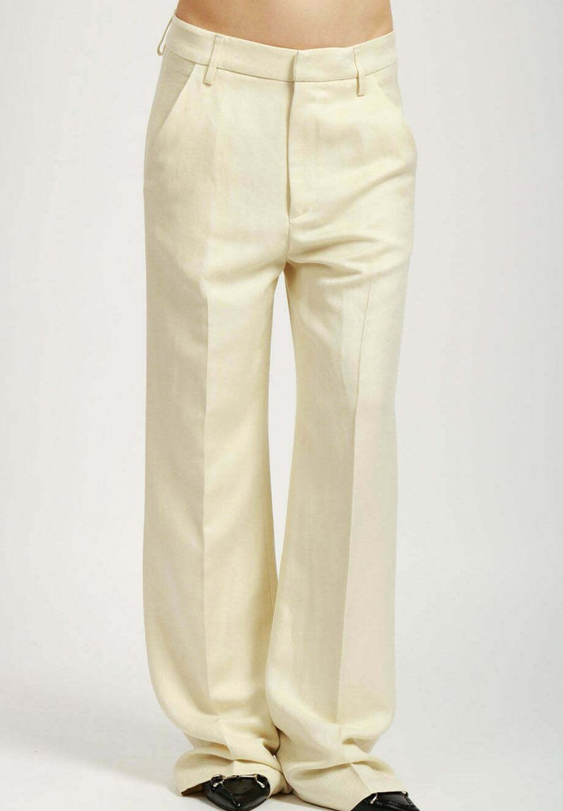 Pantalones de pierna ancha en beige claro, con una tela suave, dos bolsillos frontales y una cinturilla formal con presillas para cinturón.