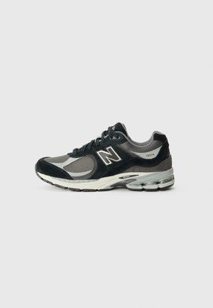 Schwarzer und grauer New Balance 2002R Laufschuh mit Mesh- und Wildleder-Obermaterial, weißer Zwischensohle und gedämpfter Außensohle mit sichtbaren Stützpolstern.