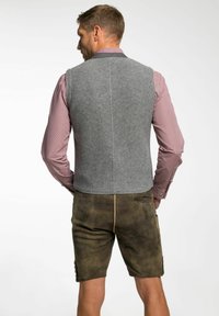 Graue Wollweste mit strukturierter Oberfläche, über einem pinken karierten Hemd getragen, kombiniert mit braunen Shorts mit Seitentaschen und Knopfdetails.