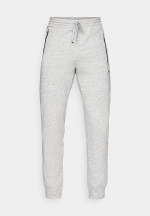 Grå sportsbukser lavet af blødt materiale, med elastisk talje og snoretræk, lynlåslommer i siderne og tætsiddende muffer.