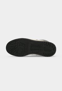Μαύρη λαστιχένια σόλα αθλητικού Adidas με ανάγλυφο σχέδιο πέλματος και λογότυπο Adidas, το παπούτσι είναι τοποθετημένο επίπεδα με τη σόλα προς τα πάνω.