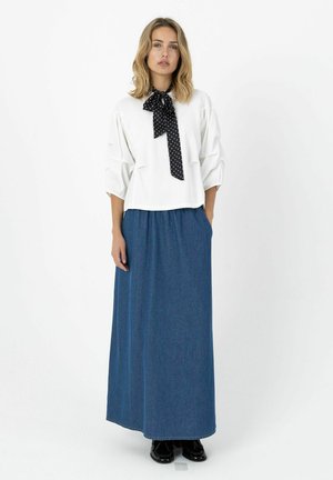 Weiße Bluse mit Puffärmeln und einer schwarzen Schleife mit Polka-Dots, kombiniert mit einem langen blauen Jeansrock mit Seitentaschen und glatter Oberfläche.