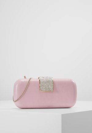 Vaaleanpunainen suorakaiteenmuotoinen käsilaukku pyöristetyillä reunoilla, jossa on strassilla koristeltu lukko ja kultainen ketjuhihna, esillä valkoisella pinnalla.