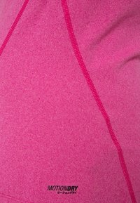 Fuksia urheilukangas, jossa on heather-tekstuuria, sisältää erottuvan vaaleanpunaisen ompeleen ja mustan "MOTIONDRY"-merkin pohjassa.