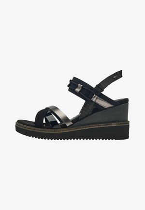 Kilesandal med sorte og metalliske stropper, en justerbar ankelrem og en tekstureret kilehæl for ekstra stabilitet.