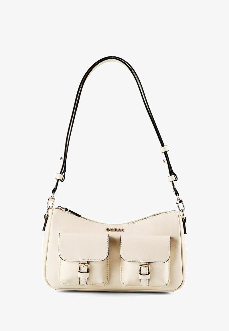 Sac d'épaule couleur crème avec deux poches avant à boucles et une fine bandoulière noire, arborant un petit logo "GUESS" en lettres métalliques.