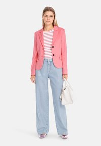 Pink blazer with a single button, paired with a white and red striped shirt. Light blue wide-leg jeans and shiny pink shoes. White handbag.