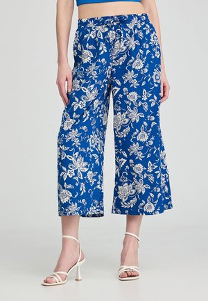 Pantaloni culotte a fantasia floreale blu con vita elasticizzata e gambe larghe, realizzati in tessuto leggero. Accentuati da fiori bianchi.