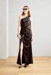 Melna satīna kleita ar vienu plecu, drapēts dizains, augsts šķēlums un pieguļošs viduklis. Pāris ar aizsistām purngaliem un mazu mašīnu.