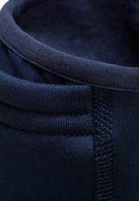 Donkerblauwe stoffen kraag met een gladde textuur, voorzien van een dubbellaags ontwerp en zichtbare stiksels langs de rand.