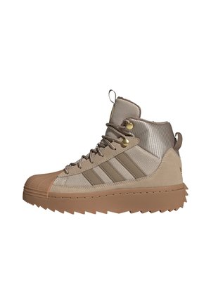 Sneaker high-top beige e marrone con suola testurizzata, chiusura frontale con lacci e dettagli laterali a righe.