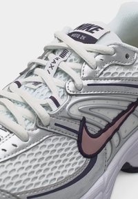 Αθλητικό παπούτσι Nike Air Max 2K σε λευκό και γκρι με επάνω μέρος από δίχτυ, λευκά κορδόνια και ροζ περιγραμμικό λογότυπο Nike Swoosh στο πλάι.