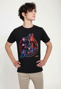 Schwarzes T-Shirt mit einem bunten Grafikdesign von Marvel-Charakteren innerhalb eines runden Logos. Glattes Material, kurze Ärmel und Rundhalsausschnitt.