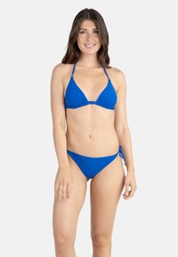 Bikini bleu avec un haut triangulaire et des bretelles ajustables ; le bas présente un design à nouer sur les côtés, une texture lisse et un style minimaliste.