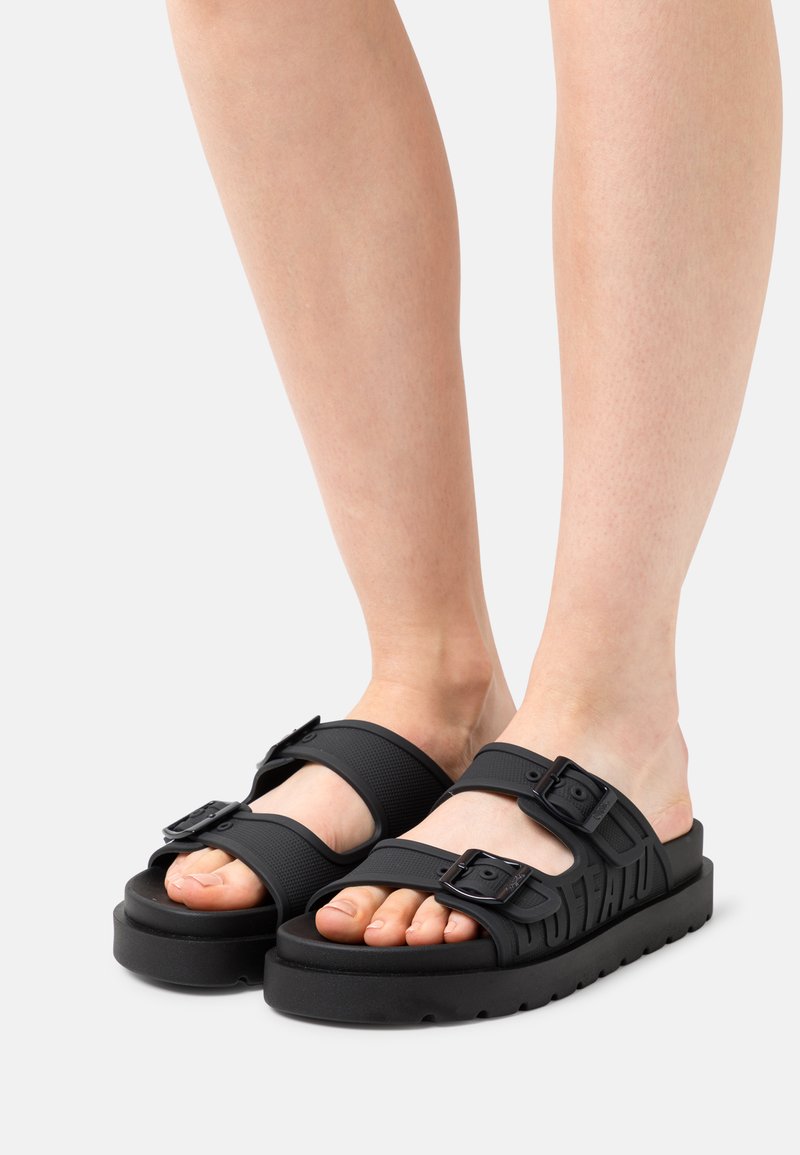Sandale negre din cauciuc cu două catarame ajustabile, talpă texturată și talpă groasă cu branding embosat pe lateral.