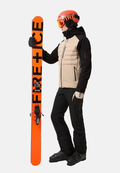 Ski-uitrusting met een beige puffy jas, zwarte broek, zwarte handschoenen, een oranje helm en een oranje snowboard met zwarte tekst.