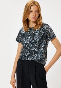 Korte mouwen top gemaakt van paillettenstof in tinten van blauw en zilver. Ronde hals, aansluitende silhouet, met een zachte textuur en glanzend oppervlak.