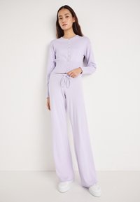 Σετ δύο κομματιών λιλά που περιλαμβάνει ένα κοντό πουλόβερ με κουμπιά και υφή με ρίγες, καθώς και ταιριαστό παντελόνι με ευρύ πόδι και κορδόνι στη μέση.