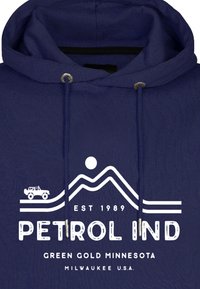 Felpa blu navy con un design grafico bianco che ritrae montagne, sole e la silhouette di un jeep. Include il testo "PETROL IND" e la localizzazione.