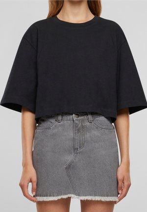 Sort croppet t-shirt med korte ærmer, kombineret med en grå denim mini-nederdel med frynset kant og forlommer.